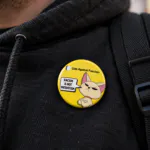 Racism Is Not Patriotism badge- Cats Against Fascism- Racism is not Patriotism Button Pin Badge, UK Political Merch, Yellow Badge with angry cat saying "Racism is not Patriotism" with Cats Against Fascism Text and Logo above Mock up on Black Hoody